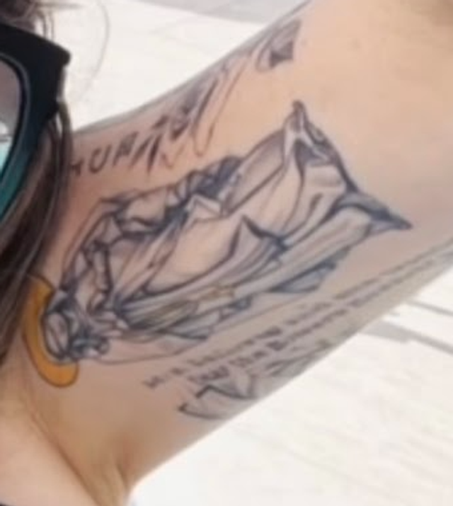 Close-up detail of the poolside frame: a black-and-grey mountain-landscape scene with script lettering above and below it on the inner upper arm.