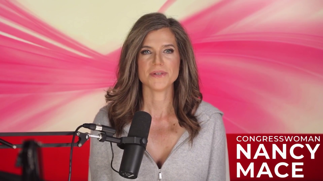 Still: Mace at a boom microphone, red-and-pink studio backdrop, CONGRESSWOMAN NANCY MACE lower-third