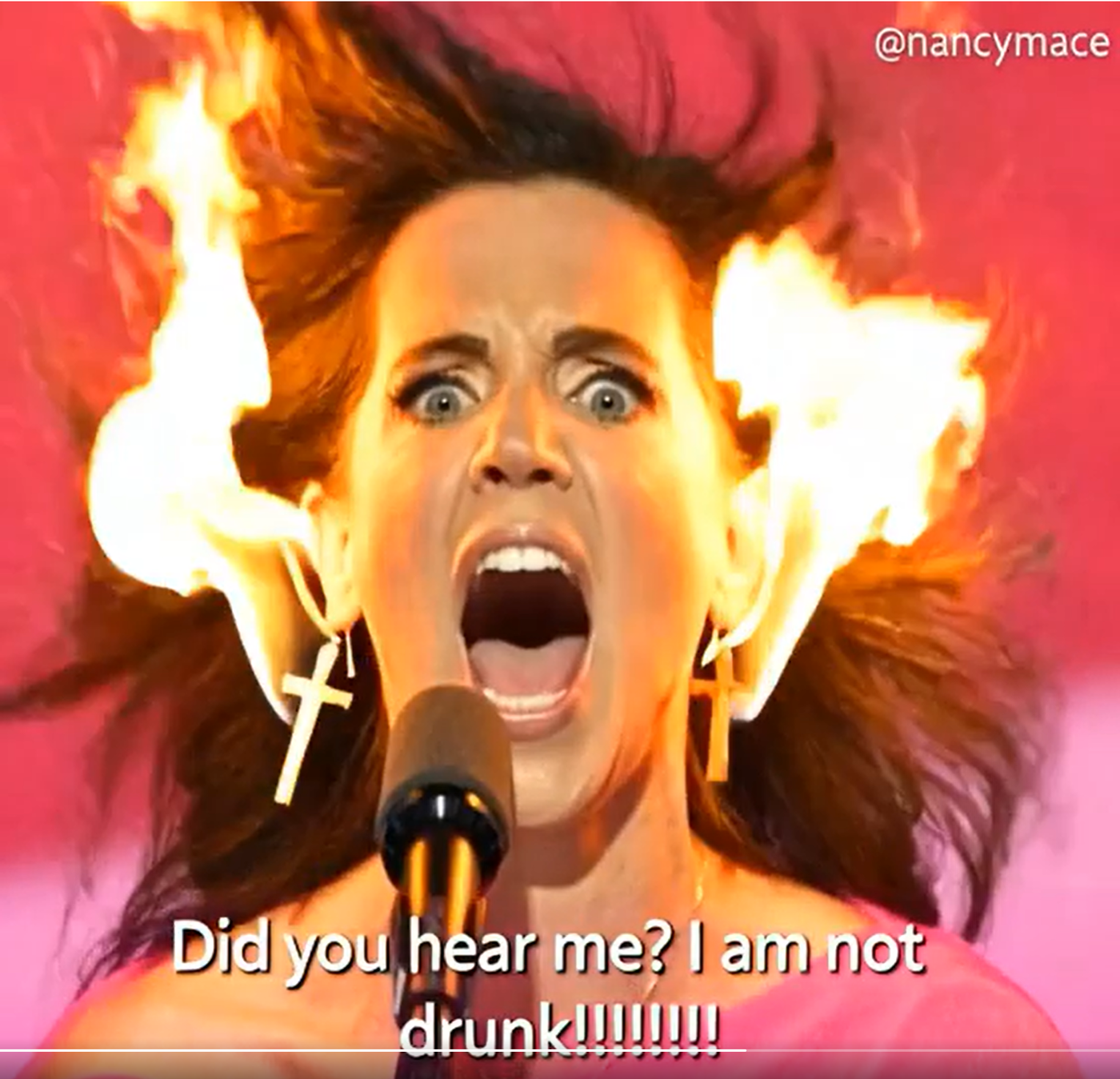 A frame from Endora's Grok Imagine video: an AI-stylized Nancy Mace figure with hair and earrings on fire, labeled @nancymace, over the caption 'Did you hear me? I am not drunk!!!!!!!!'